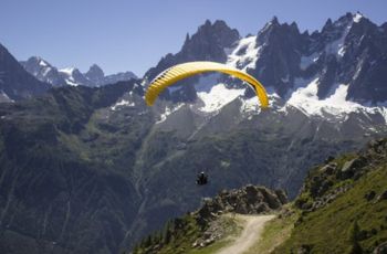 This is a photo of a person paragliding, with mountains surrounding on all sides.